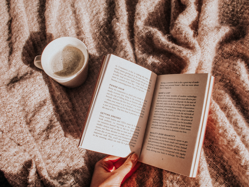 a book and cup or tea in the sunlight with a cozy tan blanket