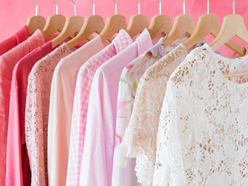 a photo of women's blouses on a clothing rack with white and pink colors